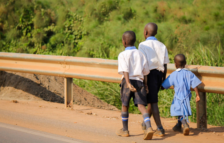 Photo of three children walking along a road.