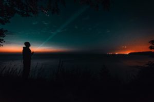 A man with a flashlight outside at night.