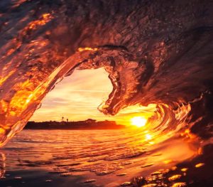 Inside a wave in the ocean with the sunset.