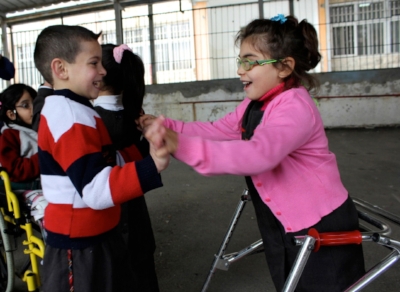 2 kids smiling and holding hands.