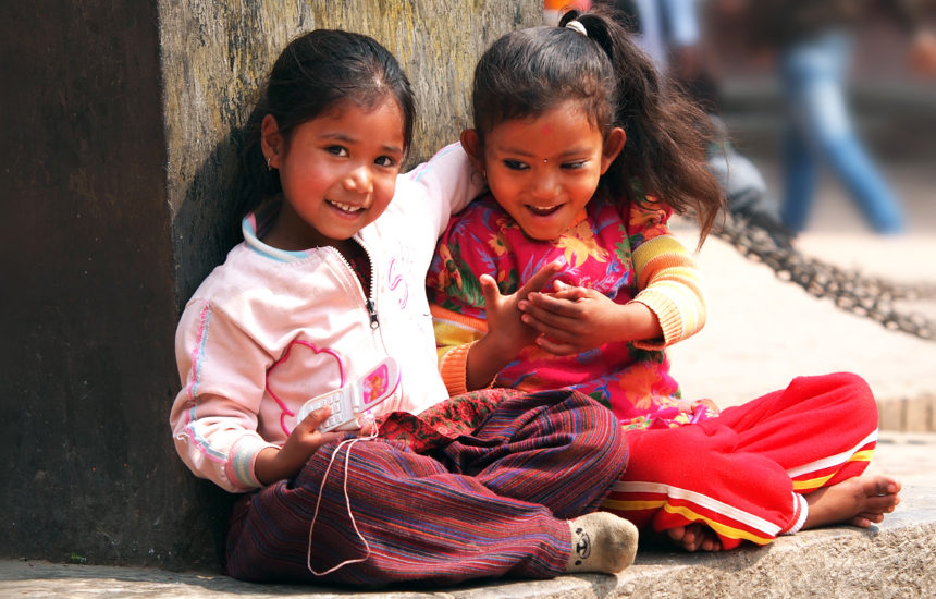 2 young girls with their arm around each other, smiling.