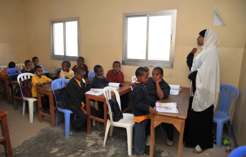 Children listening to a teacher in a classroom.