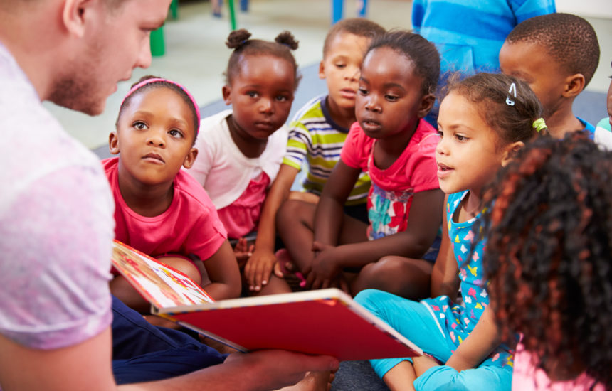 A group of kids listening to a story being read to them.