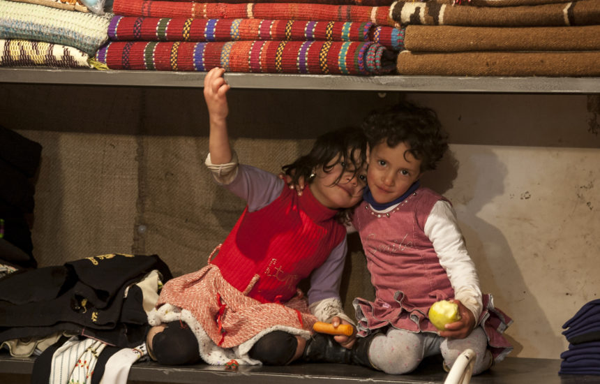 2 kids hugging while holding food.