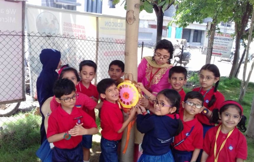 Children taping a picture up to a tree