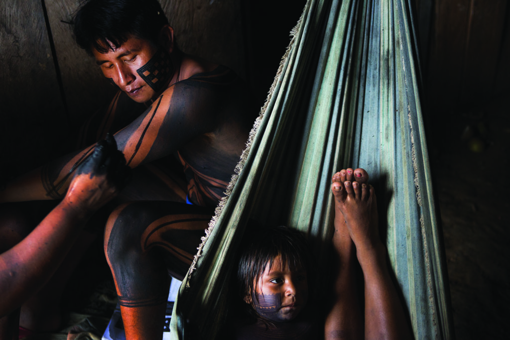 A young boy sits in a hammock with an older man next to him