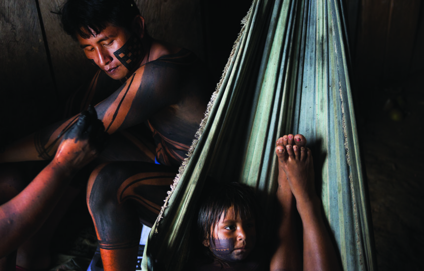 A young boy sits in a hammock with an older man next to him