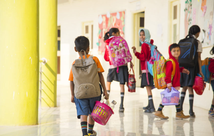 Children in a school walking with backpacks on