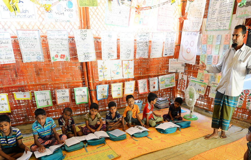 A man teaching to a group of children with books