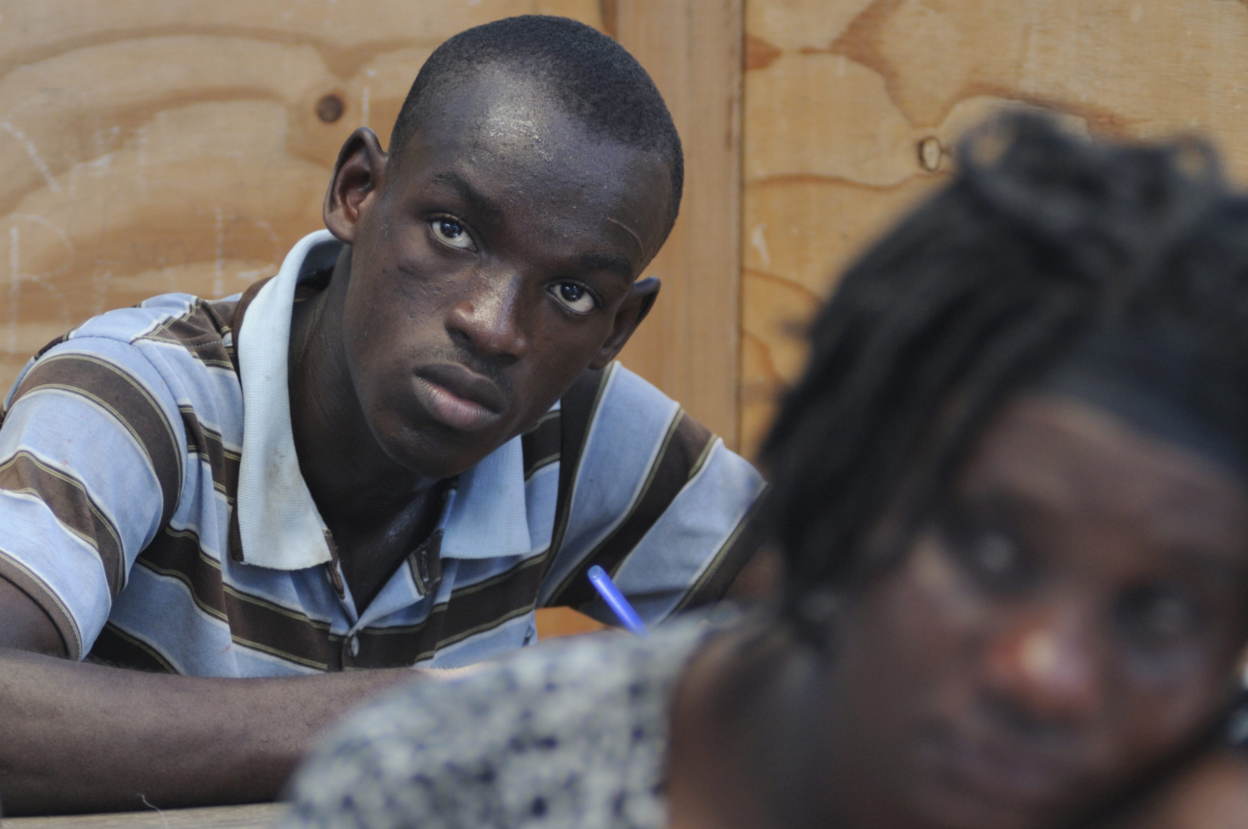 Photo of young man holding a pen and looking up in a classroom