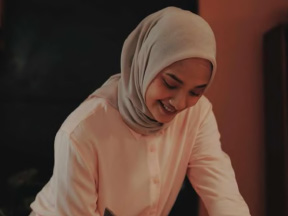 A woman smiles and writes in a journal