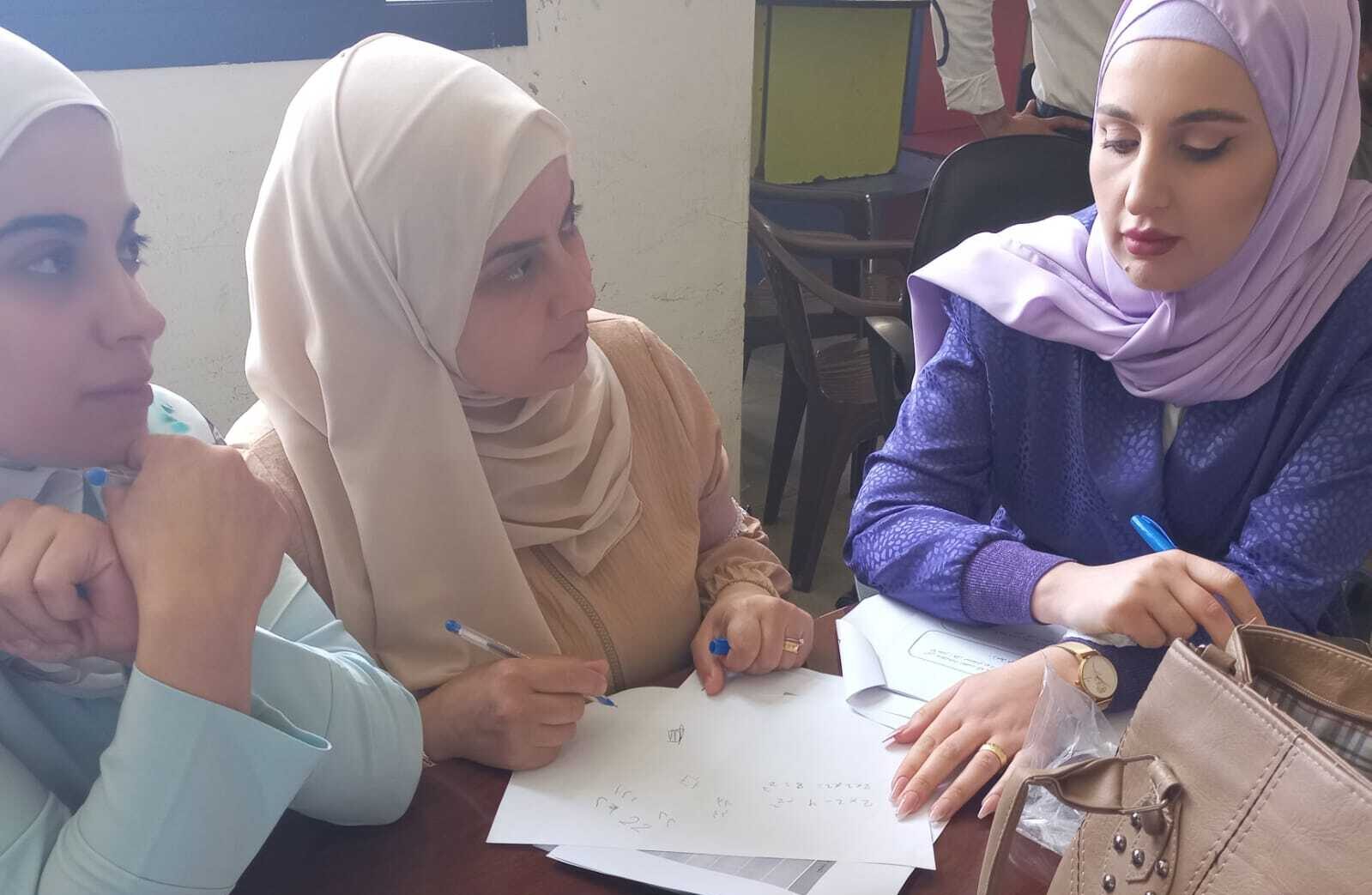 Three women collaborating and writing shared notes.