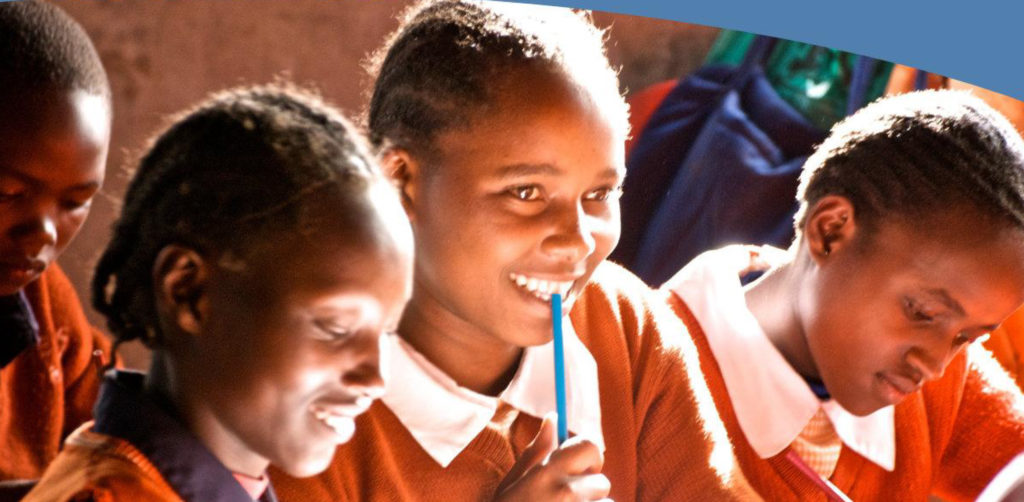 Four children sitting close together in class