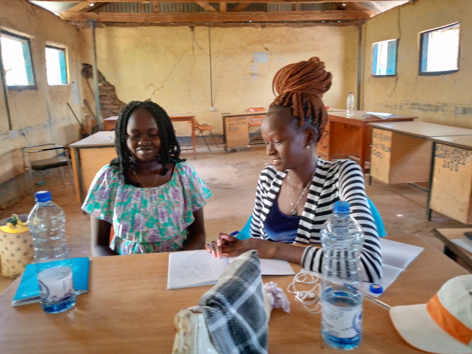 Photo of a teacher with a student, sitting at a table, working together in an empty classroom