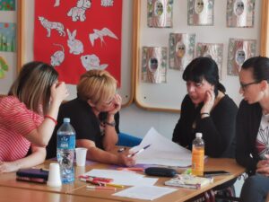 Four teachers sitting at a table, actively discussing and looking at papers