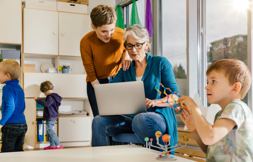 Pre-school teachers with laptop talking in kindergarten