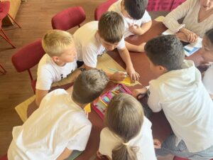 Six students and a teacher, gathered around a table, with colored pencils in hand, collaborating on a project.