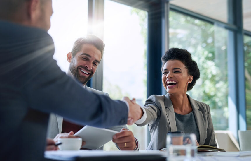Smiling education leaders and ministry of education officials shaking hands and collaborating.