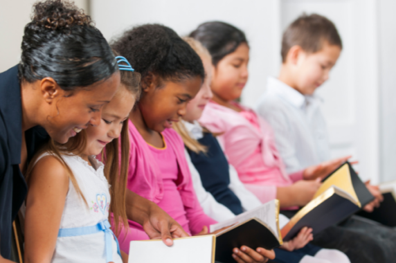 A happy teacher helping students read